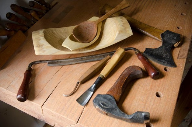 a wooden bowl with hand tools